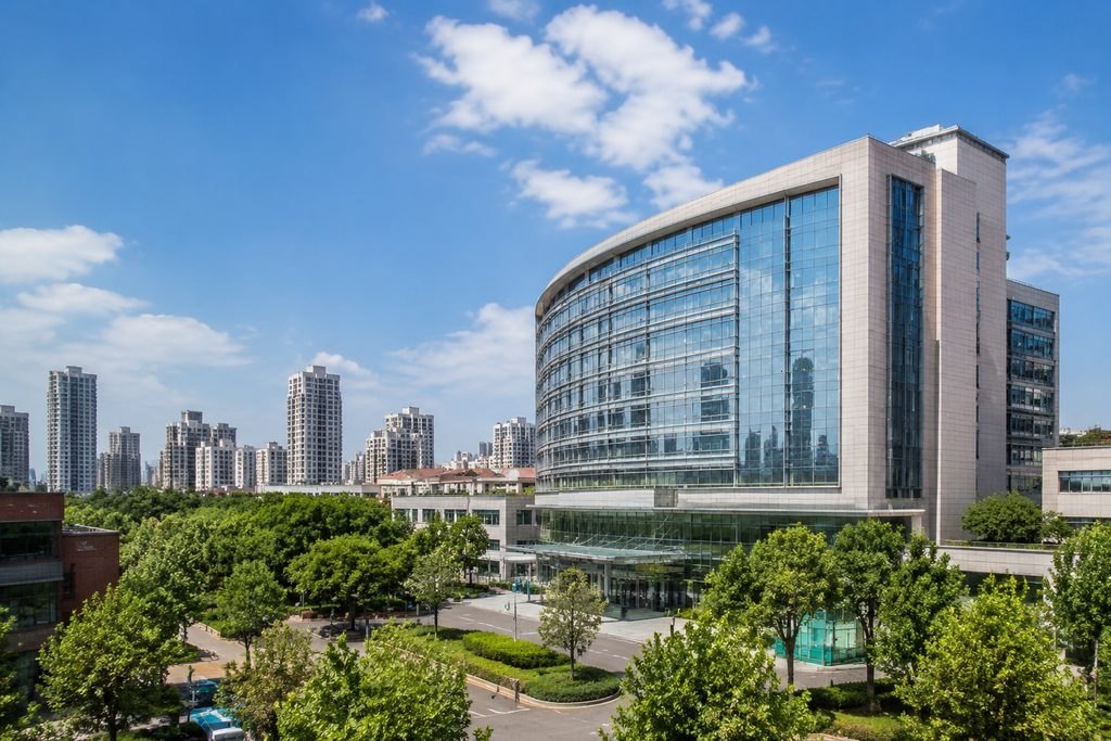 Illustrative image: A modern hospital building surrounded by greenery and urban skyline.